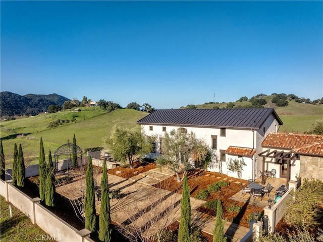 exterior space with a patio, a standing seam roof, stucco siding, a rural view, and metal roof