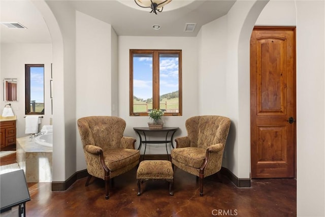 living area with arched walkways, visible vents, and concrete flooring