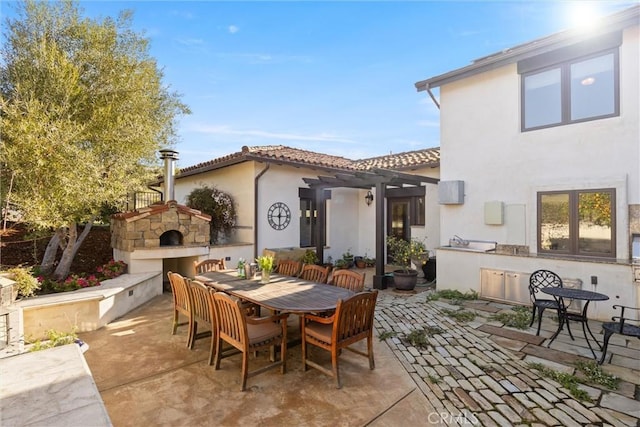 view of patio with outdoor dining area, a pergola, an outdoor stone fireplace, and area for grilling