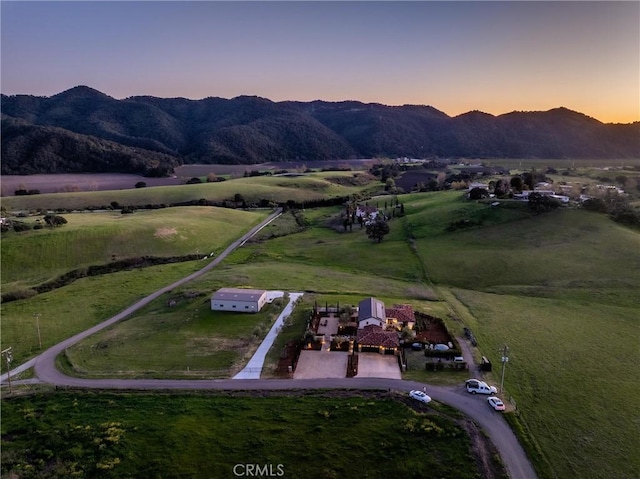 aerial view at dusk featuring a mountain view and a rural view