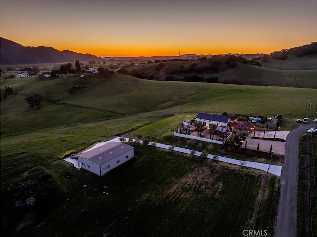 aerial view at dusk with a mountain view and a rural view