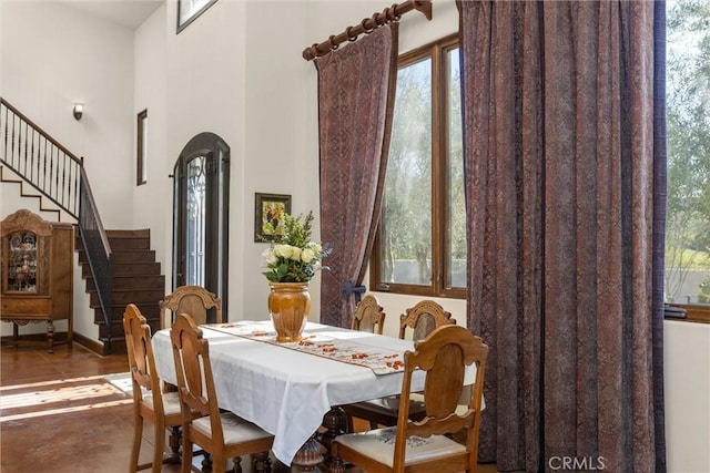 dining space with stairs and a towering ceiling