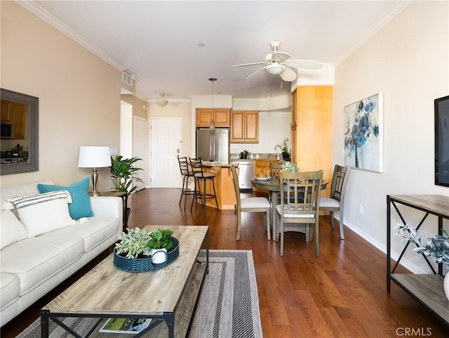 living room with visible vents, baseboards, ornamental molding, dark wood-style floors, and a ceiling fan