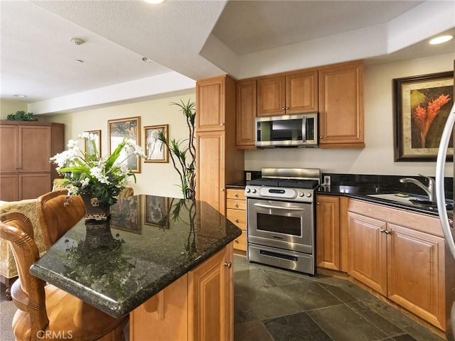 21345 Hawthorne Blvd Unit 415, Torrance, CA 90503 - kitchen featuring dark stone countertops, a kitchen island, a sink, appliances with stainless steel finishes, and brown cabinets