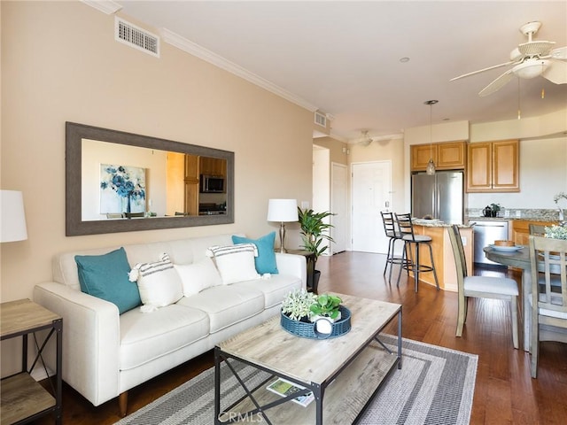 living room featuring ornamental molding, visible vents, dark wood-style flooring, and ceiling fan