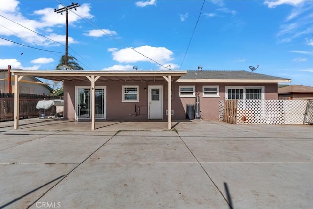 rear view of property featuring stucco siding, a patio area, and fence