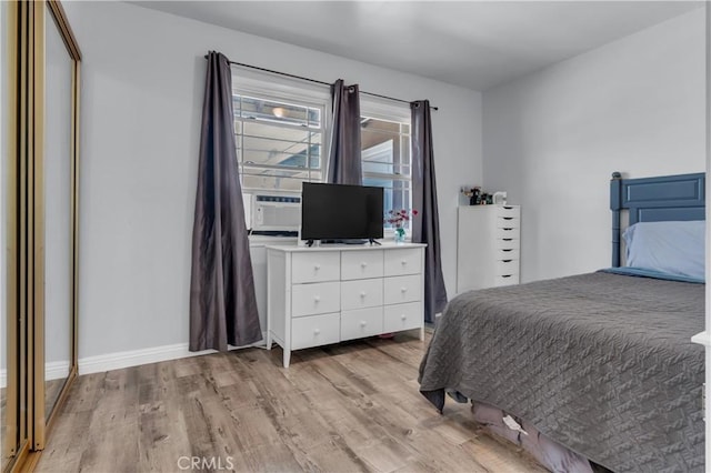 bedroom featuring light wood-style flooring, cooling unit, and baseboards