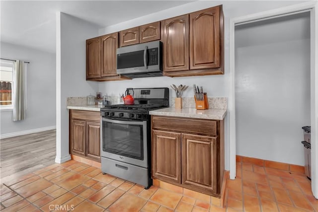 kitchen with light tile patterned floors, baseboards, and appliances with stainless steel finishes