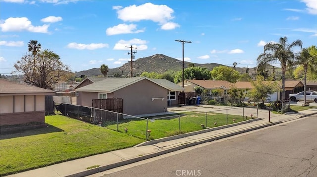 view of front of house with fence, a residential view, stucco siding, a front lawn, and a mountain view