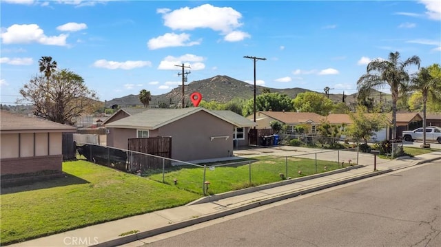 view of front of property with stucco siding, a front lawn, fence, a mountain view, and a residential view