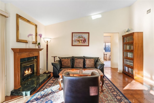 living area featuring vaulted ceiling, a fireplace, and visible vents