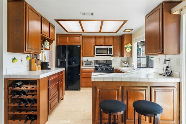 kitchen with visible vents, black appliances, a sink, open shelves, and a peninsula