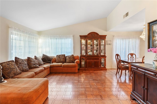 living area featuring visible vents, a healthy amount of sunlight, and vaulted ceiling