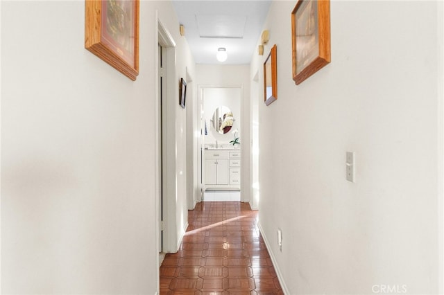 hall with attic access, baseboards, and a sink