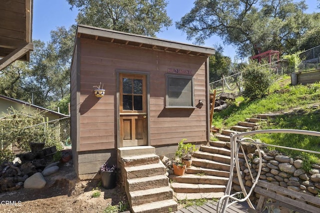 view of outdoor structure with entry steps, an outbuilding, and fence