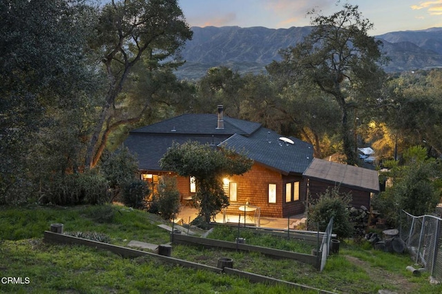 view of front facade with a garden, a patio area, a mountain view, and fence