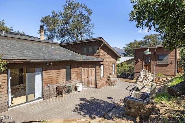 rear view of property featuring a wooden deck and roof with shingles