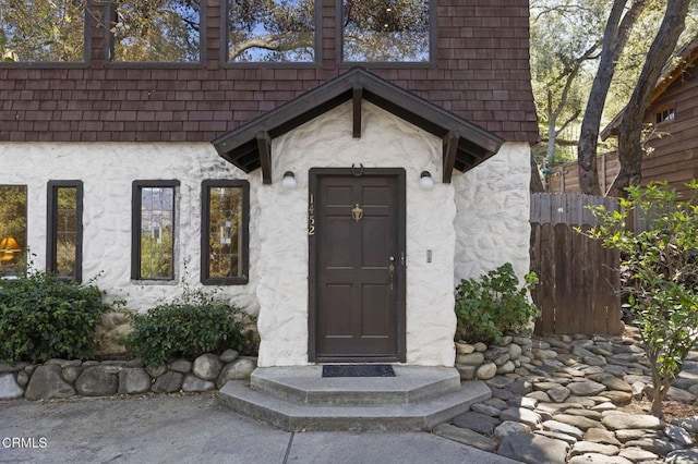 doorway to property featuring stucco siding and fence