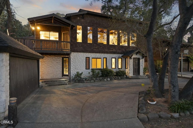 view of front of property featuring stone siding and a balcony