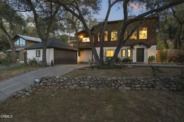 view of front facade with concrete driveway, a balcony, an attached garage, and stone siding