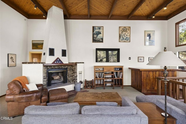 carpeted living area featuring rail lighting, beamed ceiling, wood ceiling, and a fireplace