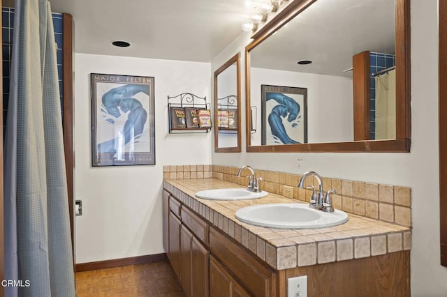 bathroom with a sink, baseboards, and double vanity