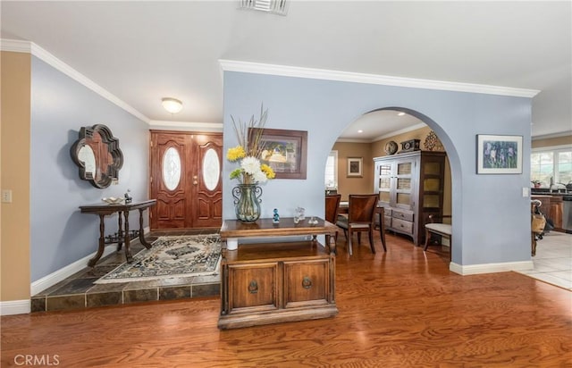 foyer entrance with wood finished floors, visible vents, arched walkways, and baseboards