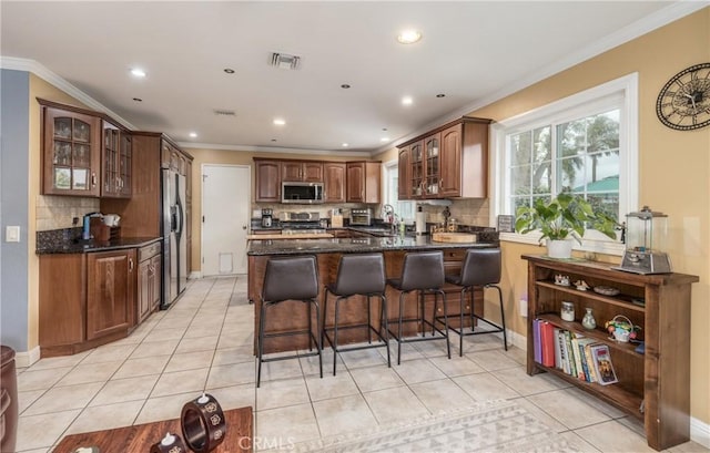 kitchen with visible vents, light tile patterned flooring, a sink, stainless steel appliances, and glass insert cabinets