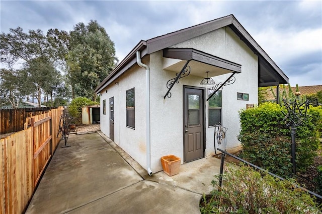 exterior space with a patio, fence, and stucco siding