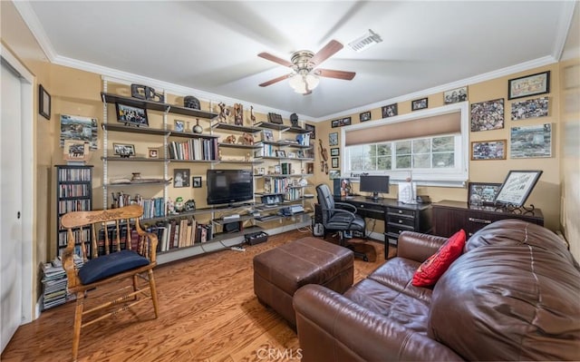 living room with ceiling fan, visible vents, wood finished floors, and ornamental molding