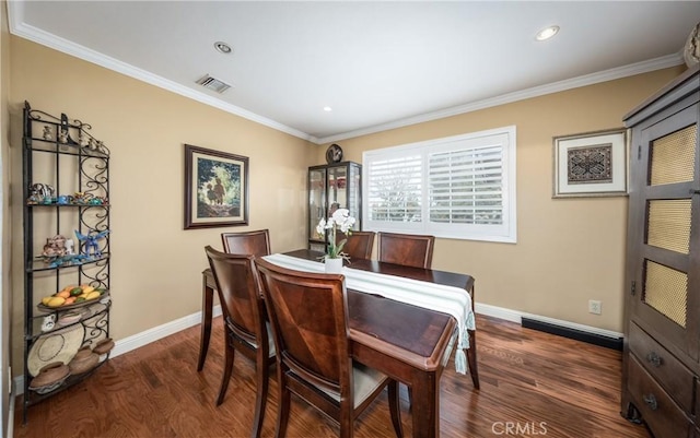 dining area with dark wood-type flooring, crown molding, baseboards, and visible vents