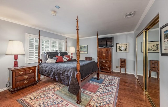 bedroom with visible vents, baseboards, wood finished floors, and crown molding