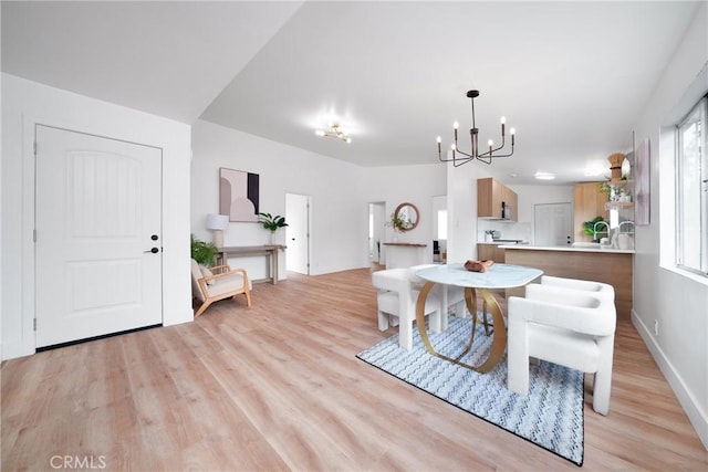 dining area with baseboards, a notable chandelier, and light wood finished floors