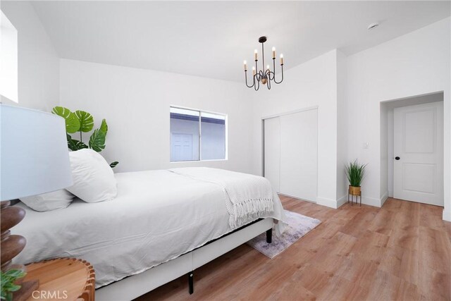 bedroom with a closet, baseboards, a notable chandelier, and light wood finished floors