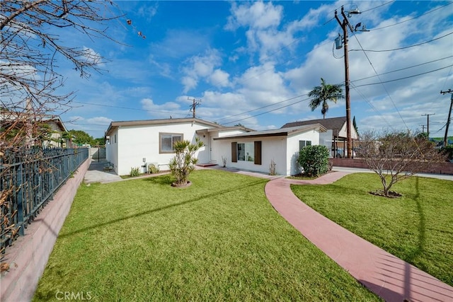 rear view of property with stucco siding, a lawn, and fence