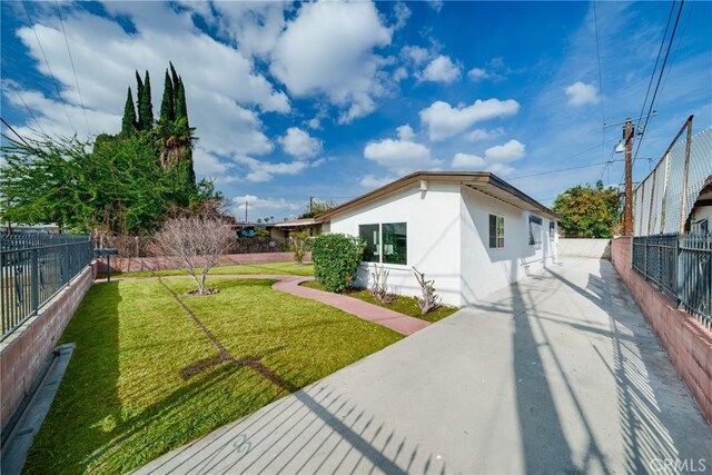 view of front of home featuring a fenced backyard, stucco siding, and a front yard