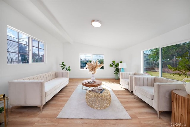 living area with lofted ceiling with beams, baseboards, and light wood-type flooring