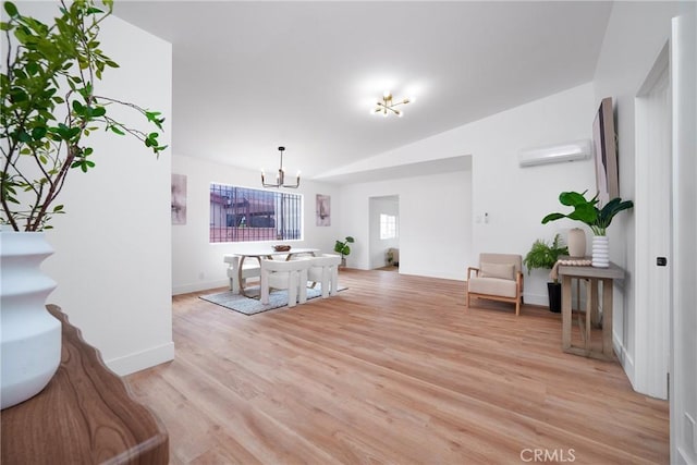 living area with baseboards, an AC wall unit, vaulted ceiling, a notable chandelier, and light wood-type flooring