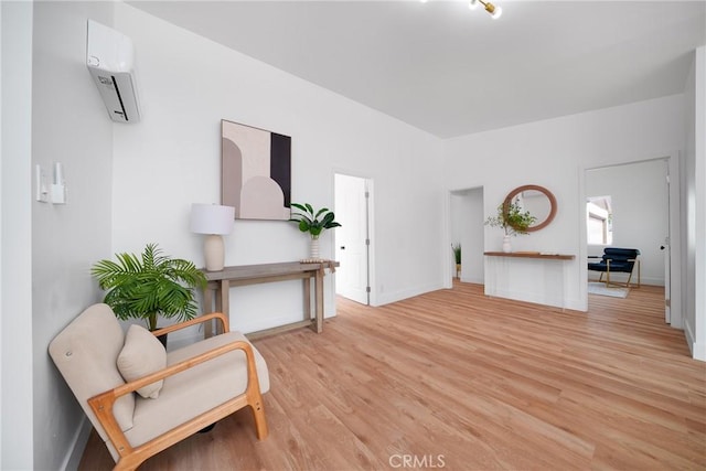 living area with baseboards, light wood-style flooring, and a wall mounted AC