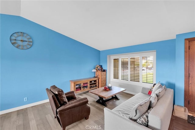 living area with baseboards, lofted ceiling, and light wood-style flooring