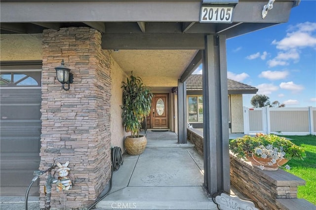 doorway to property featuring stone siding and fence