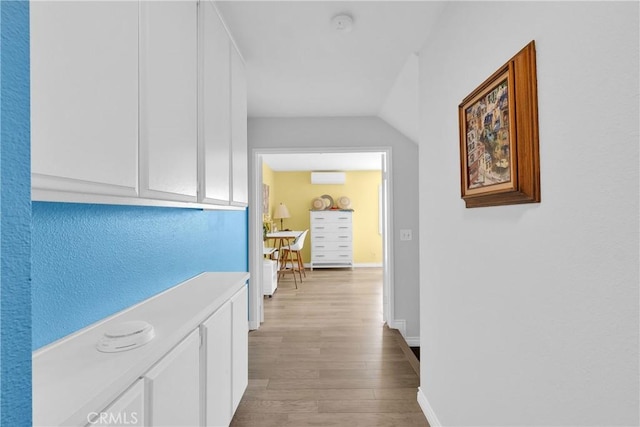 corridor featuring wood finished floors, baseboards, and a wall mounted AC