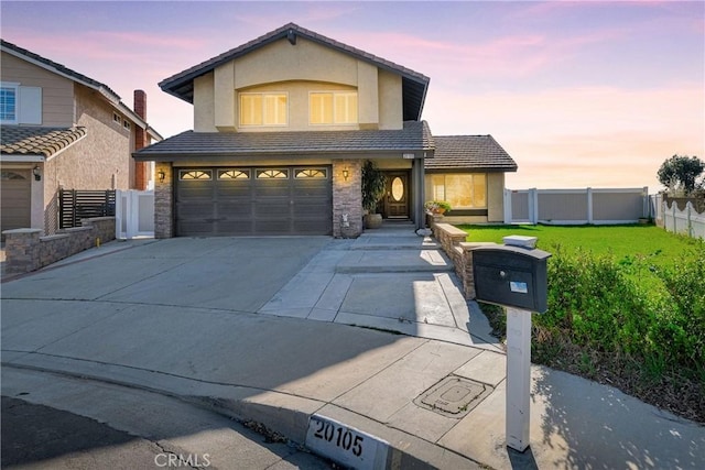 traditional home with stucco siding, a front lawn, driveway, stone siding, and fence