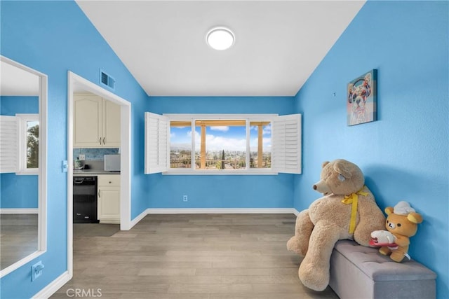 living area featuring a wealth of natural light, visible vents, baseboards, and light wood-style floors