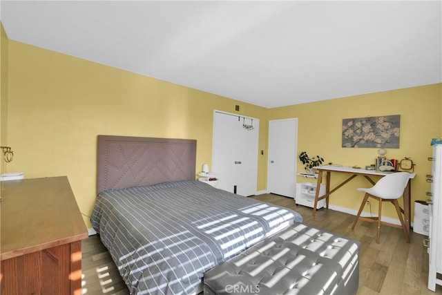 bedroom featuring visible vents, baseboards, and wood finished floors