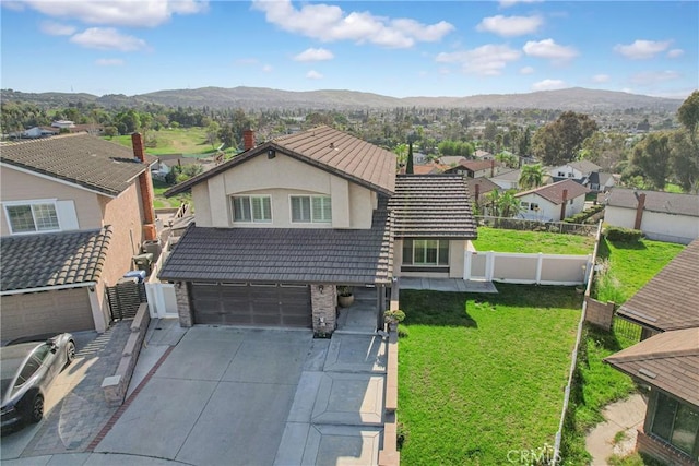 view of front facade with concrete driveway, a tiled roof, fence, and a mountain view