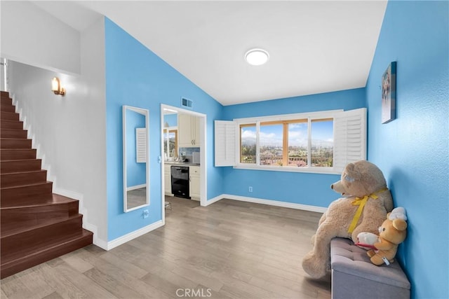 living area featuring baseboards, stairs, lofted ceiling, and wood finished floors