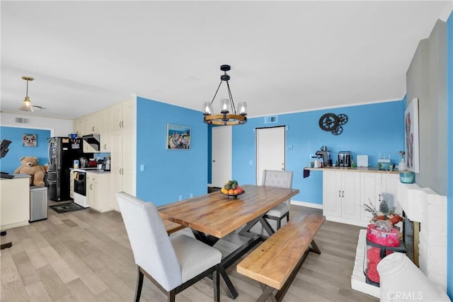 dining room featuring light wood finished floors, a chandelier, baseboards, and visible vents