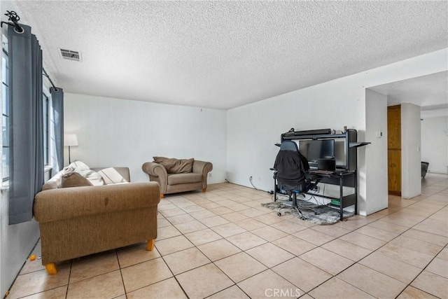 living room with light tile patterned flooring, visible vents, and a textured ceiling