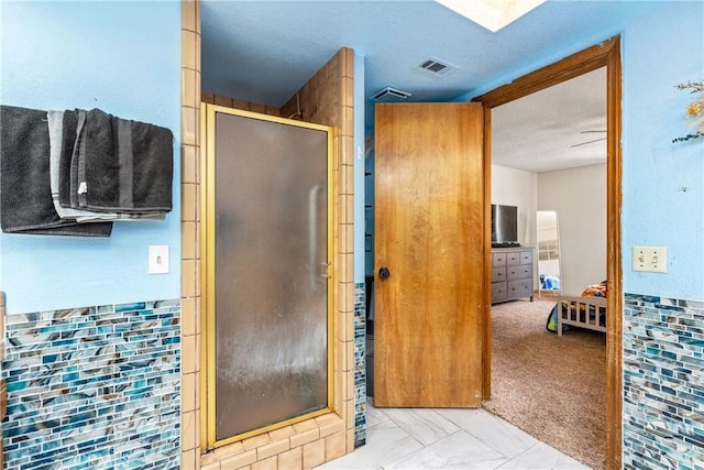 bathroom with a textured ceiling, visible vents, and a stall shower